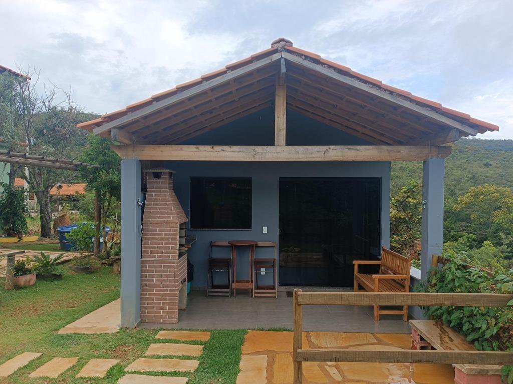 Chalé com varanda coberta, churrasqueira de tijolos e a serra ao fundo